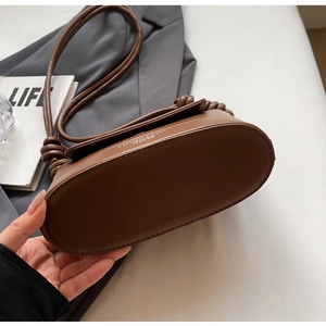 Close-up of dark brown leather handbag with fashion style lettering and knotted strap detail