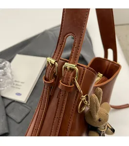 Detail of vintage brown bucket bag with shiny gold hardware and knit rabbit charm