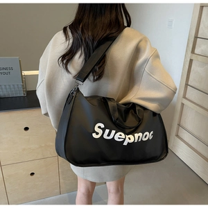 Rear view of a model carrying the large black travel bag with Suepnoc print in a room