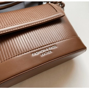 Detail of brown leather texture with vertical stripes and printed fashion logo on bag