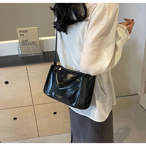 Détail du sac à bandoulière en cuir ciré noir vintage avec lettrage doré de la marque