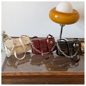 Close-up of stylish retro crossbody bags in cream, red, and black with metallic chain