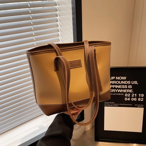 Detail of contrast stitching and leather brand label on a two-tone retro tote bag