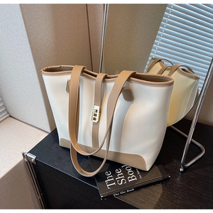 Detail of two-tone tote bag with ivory faux leather and brown trim plus gold buckle