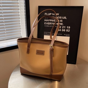 Detail of two-tone khaki and brown leather tote bag with vintage metal hardware