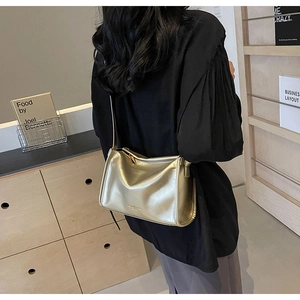 Détail d'un sac oreiller doré métallisé avec fermeture éclair et fine bandoulière