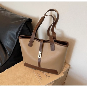 Detail view of khaki and brown tote bag with metal buckle on a minimalist stone stand