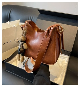 Brown vintage style bucket bag in a black gift box with a woven rabbit charm detail