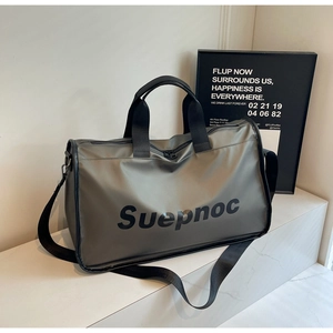 Detail of silver travel bag with black handles and adjustable shoulder strap on stairs