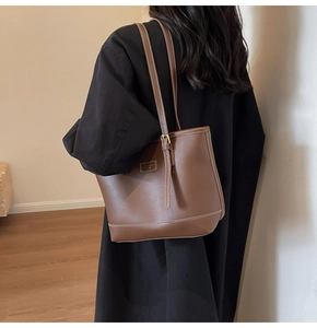 Detail of dark brown leather tote bag featuring white contrast stitching and adjustable strap