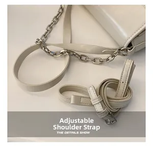 Detail view of the adjustable shoulder strap and silver chain on a cream crossbody bag