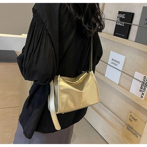 Détail d'un sac oreiller plissé doré avec bandoulière porté par un mannequin en intérieur