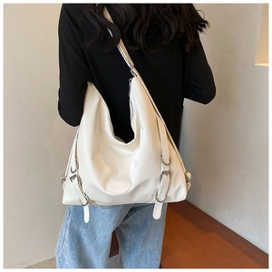 Vista posteriore di una modella con borsa hobo crema grande con bordo ondulato e fibbie