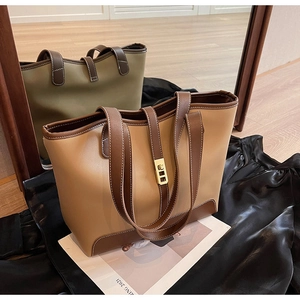 Detail view of khaki and dark green tote bags featuring white stitching and gold metal buckles