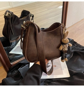 Close-up of retro dark brown hobo bag with wide strap and cute rabbit pendant charm