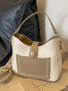 Minimalist beige bucket bag with jacquard shoulder strap and front pocket detail