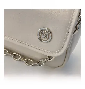 Detailed view of cream leather flap bag with silver hardware and chic metal chain strap