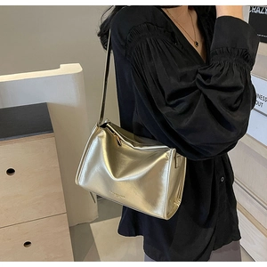 Détail d'un sac oreiller doré métallisé avec fermeture éclair et bandoulière fine
