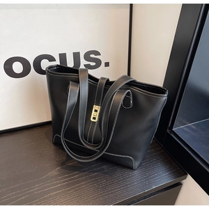 Close-up of black PU tote bag with white contrast stitching and gold metal lock
