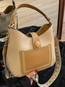 Minimalist beige bucket bag with brown pocket and patterned bohemian shoulder strap