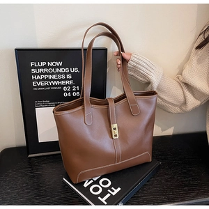 Close-up of brown leather tote bag with white contrast stitching and gold metal buckle