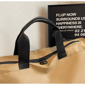 Close-up of khaki travel bag showing smooth leather texture and double black zipper detail