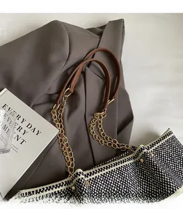 Detail of woven tote bag featuring brown leather and gold chain shoulder strap