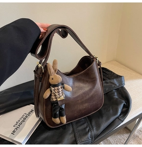 Detail of vintage brown bucket bag with a stylish houndstooth bunny charm and wide strap