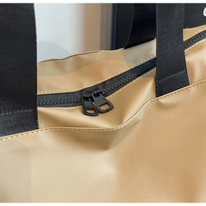 Close-up of dual black zippers and precise stitching on khaki travel bag