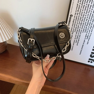 Macro detail of glossy black leather crossbody bag with silver logo and chunky chain