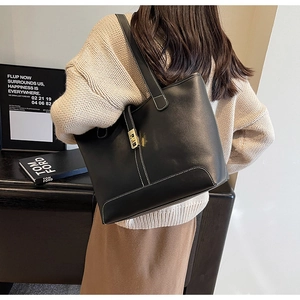 Close-up of black PU leather tote bag with white contrast stitching and gold magnetic clasp