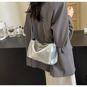 Sac bandoulière argenté moderne porté, avec une finition métallique et un design compact