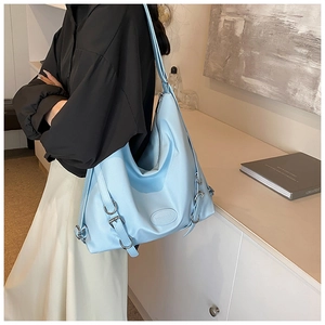 Borsa tote celeste di grande capacità con fibbie argentate indossata a spalla da modella