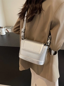 Silver pleated shoulder bag with unique knotted rope strap in a street style view