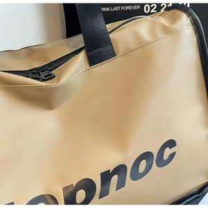 Detail of the khaki travel bag showing waterproof fabric, pnoc text, and black handle