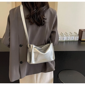 Sac oreiller argenté métallisé porté à l'épaule montrant le cuir synthétique texturé