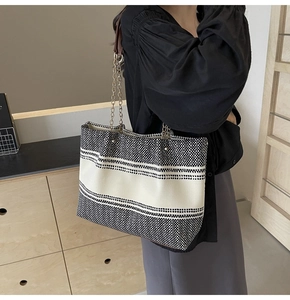 Detail of a large woven tote bag with contrast black and white pattern and chain strap
