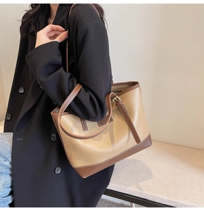Detail of color-block tote bag featuring contrast stitching and adjustable leather strap