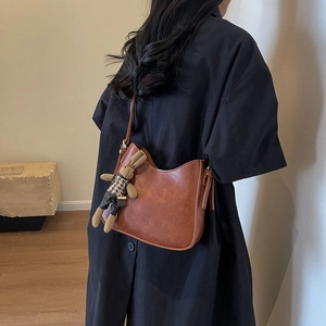 Brown semi-moon bucket bag with a cute rabbit charm shown on a black shirt model
