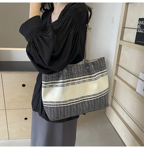 Detail of black and white tweed tote bag with gold chain and brown leather shoulder strap