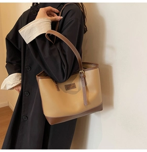 Detail of a large capacity tote bag with brown leather contrast straps and stitching