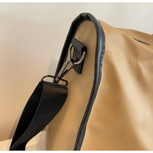 Close-up of khaki travel bag with metal hook and black shoulder strap detail