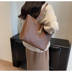 Detail of large brown tote bag with contrast stitching and gold twist lock closure