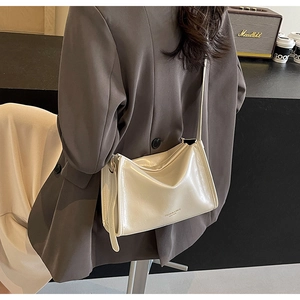 Détail du sac à bandoulière brillant crème avec un design rectangulaire plat minimaliste