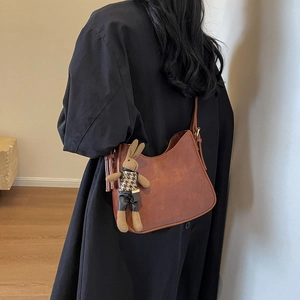 Brown half-moon hobo bag with a cute knitted bunny charm accessory and leather texture