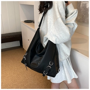 Dettaglio della borsa tote in nylon nero con fibbie argentate indossata da un modello