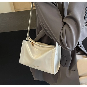 Gros plan du sac bandoulière blanc crème brillant avec fermeture éclair dorée