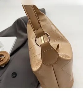 Close-up of beige PU leather shoulder bag with golden metal buckle and litchi texture