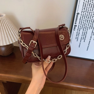 Close-up of retro burgundy shoulder bag with glossy leather texture and silver chain