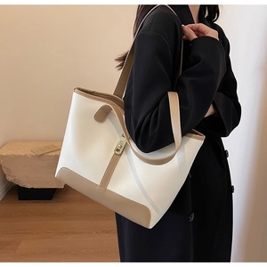 Detailed view of bicolor tote bag with golden twist-lock and camel brown strap accents